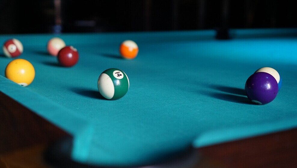 Smooth green pool table with active game of 8-ball pool